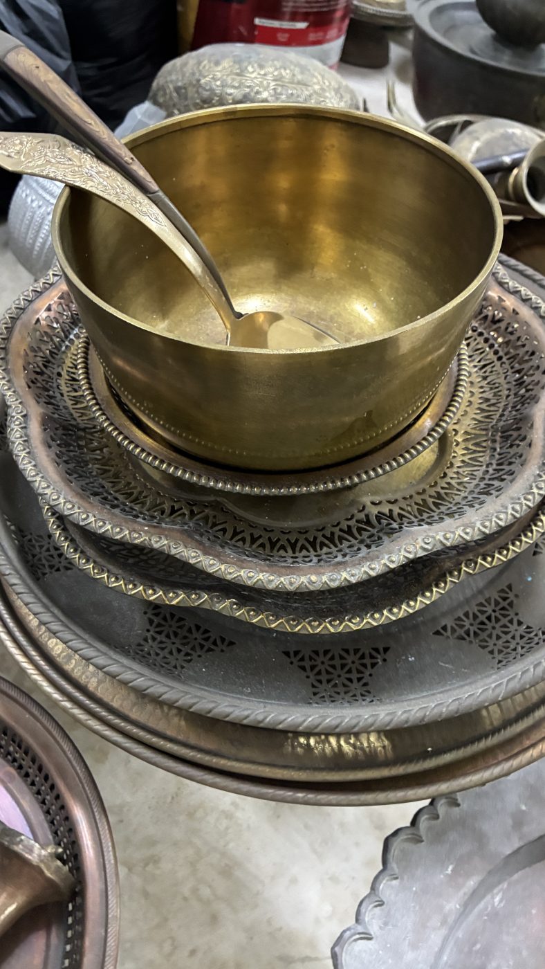 ขันทองเหลืองทรงสูงพร้อมทัพพีวางบนพานฉลุลายซ้อนหลายชั้น
